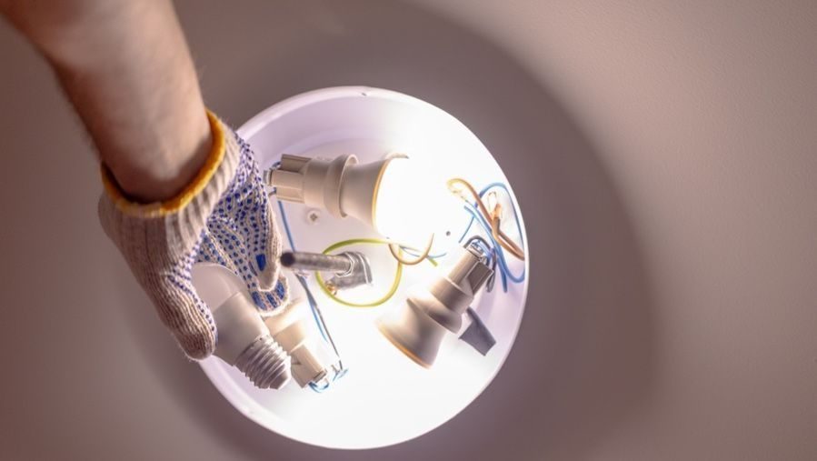 Electrician installing indoor light fixtures and ceiling lighting.