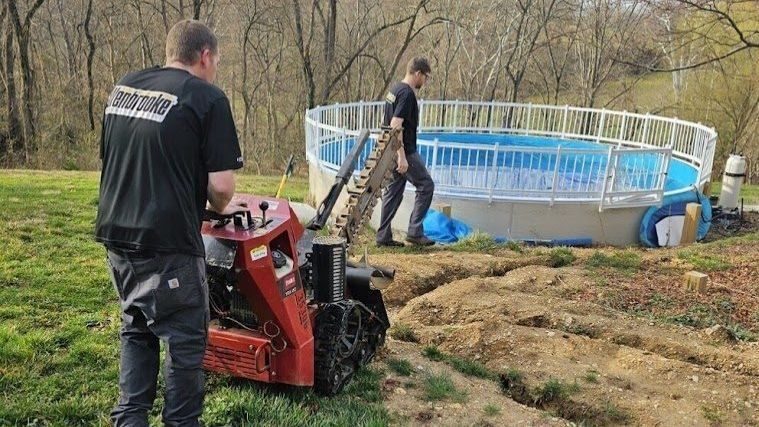 Electricians installing underground wiring near an above-ground swimming pool.